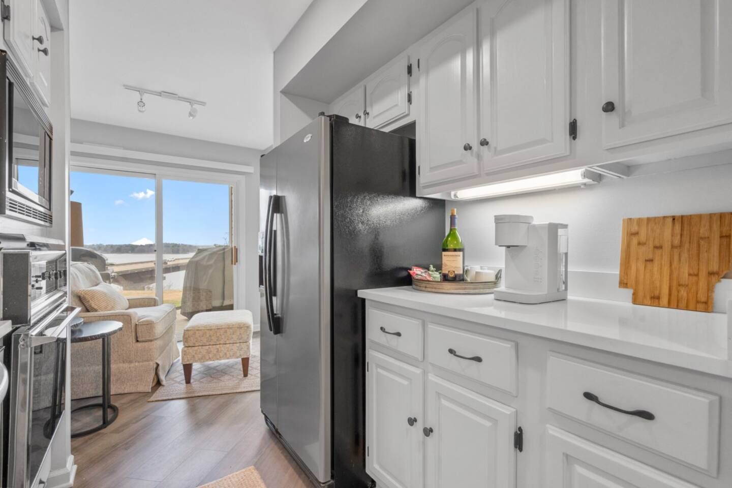 A kitchen with white cabinets and a black refrigerator.