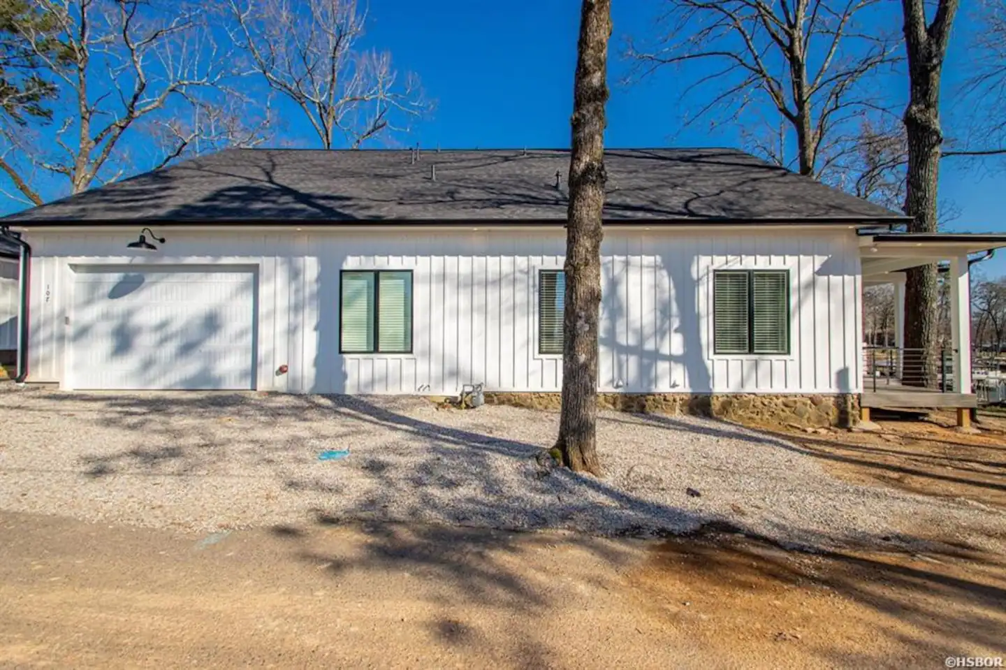 A white house with a black roof and a garage is for sale.