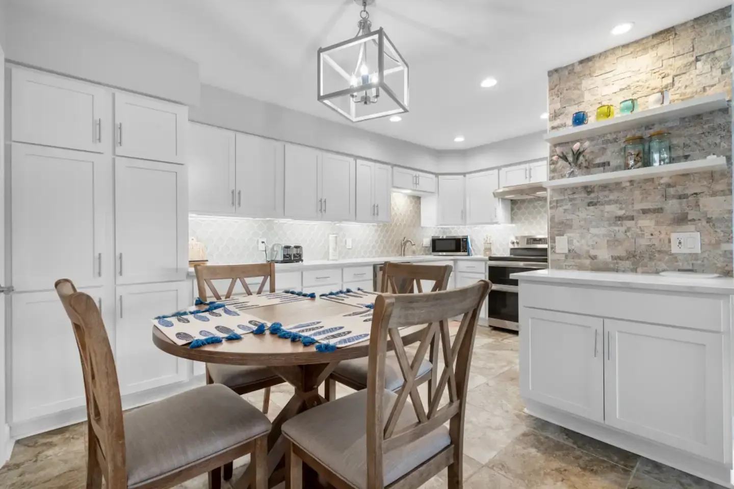 A kitchen with white cabinets , a table and chairs.