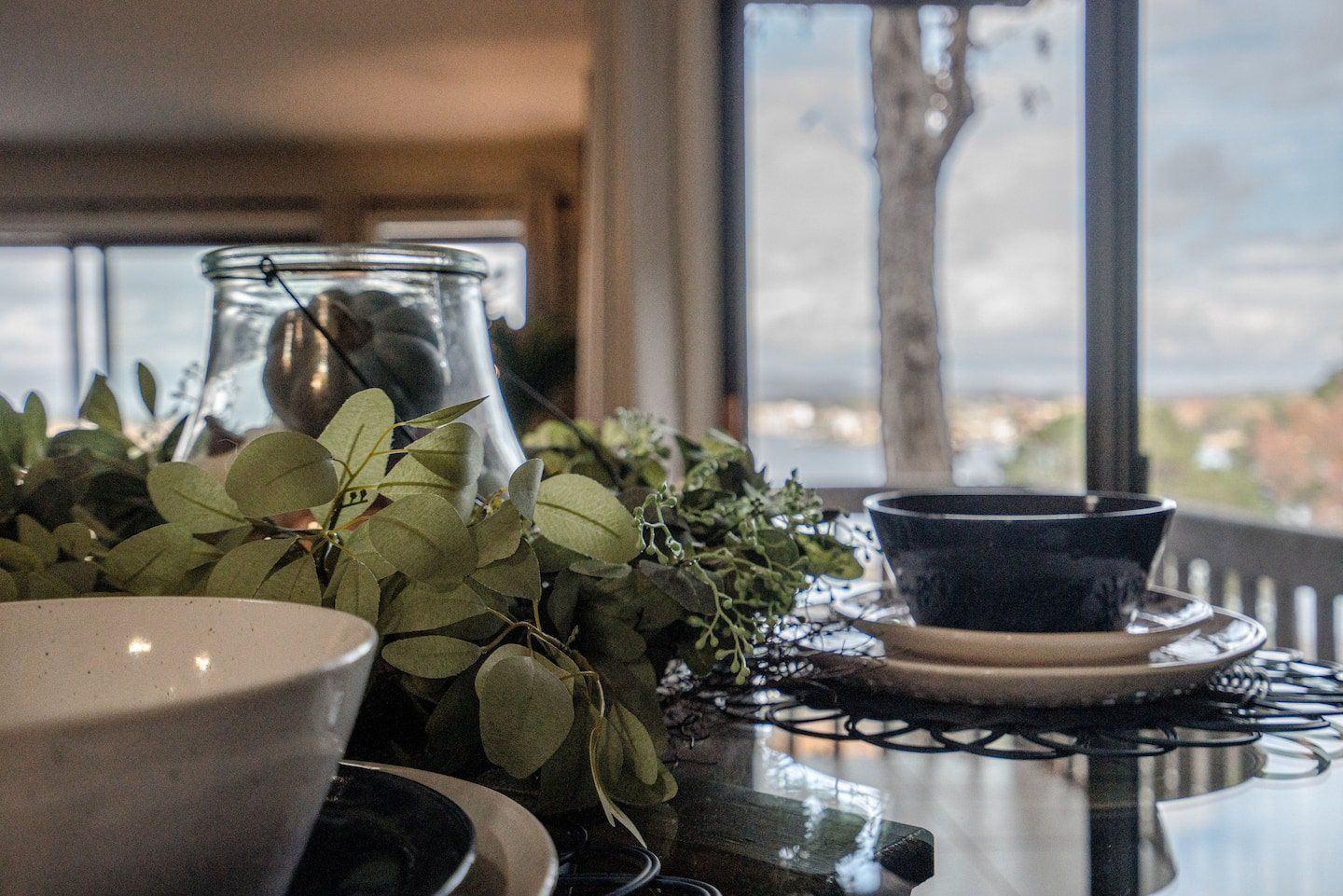 A table with bowls and plates on it and a window in the background.