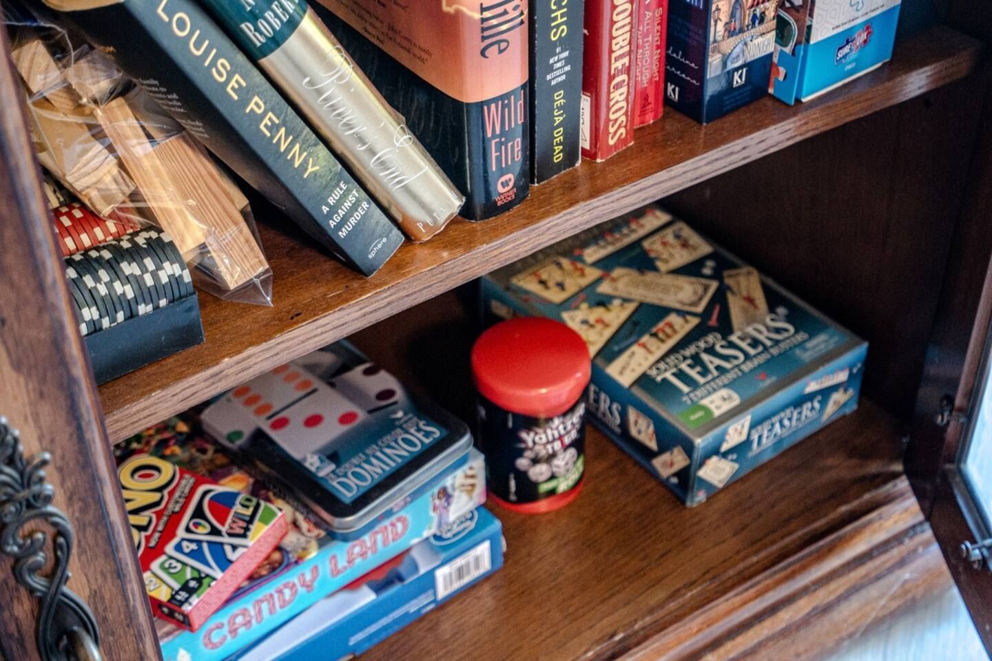 A wooden shelf filled with books and games.