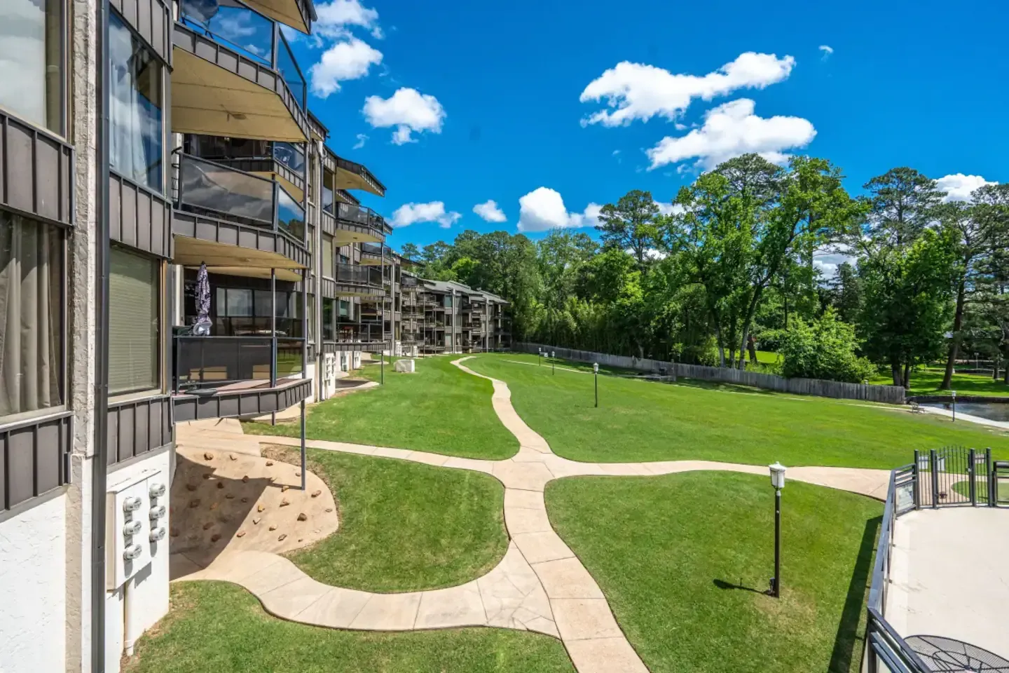 A row of apartment buildings with a lush green lawn in front of them.