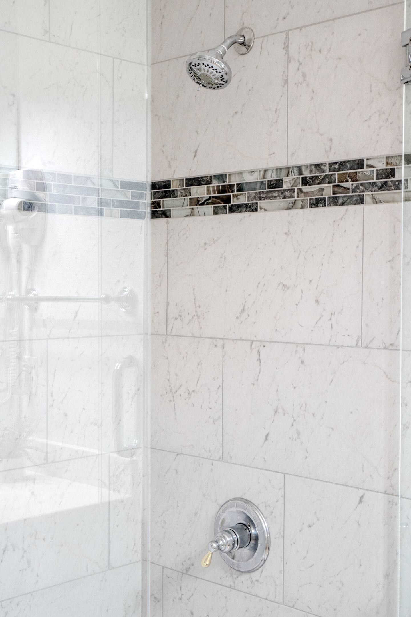 There is a shower head in the shower with a glass door.