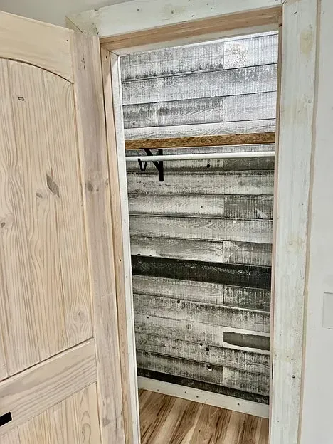 A closet with a wooden door and a wooden wall.