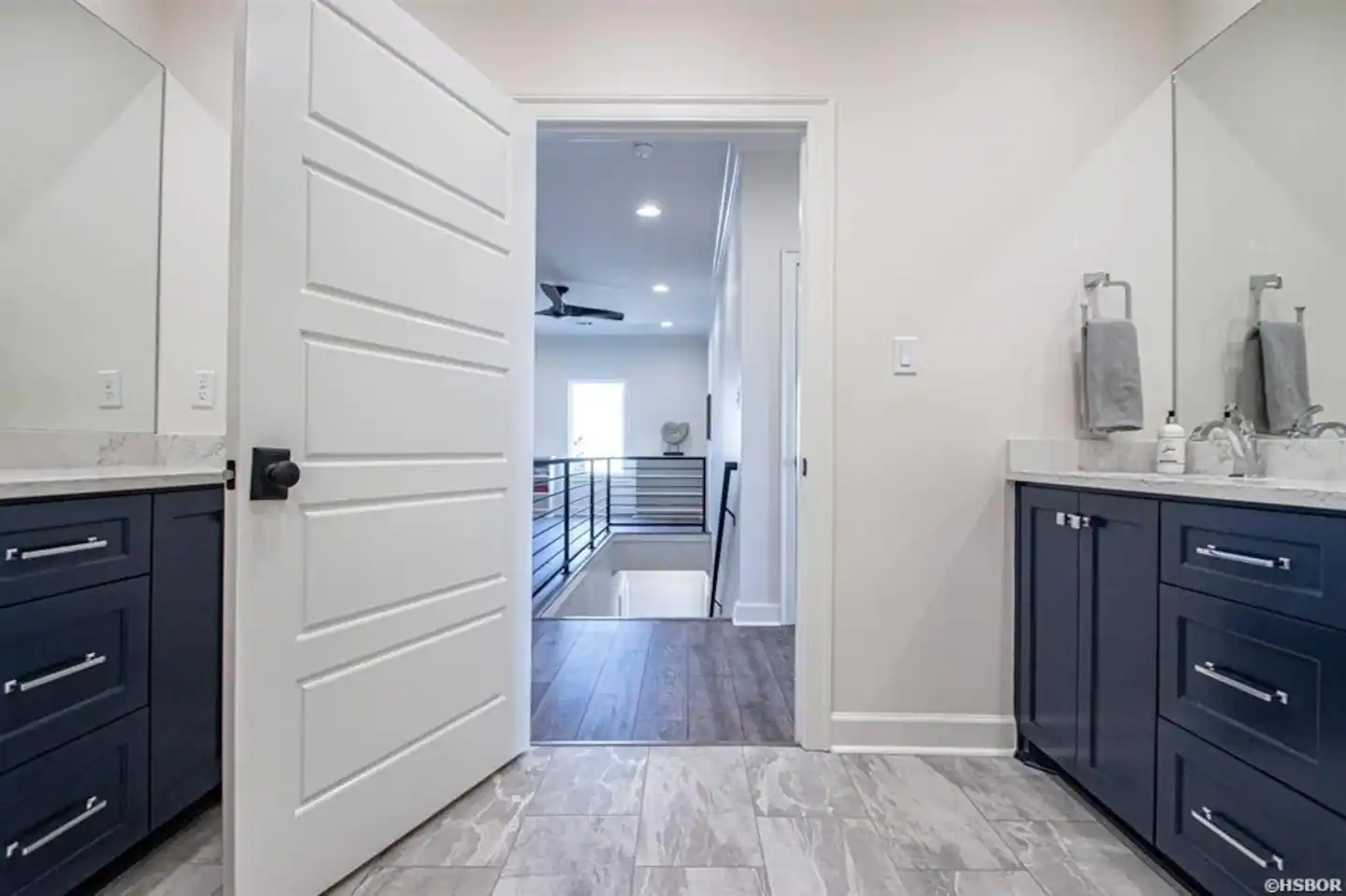 A bathroom with two sinks , a mirror and a ceiling fan.