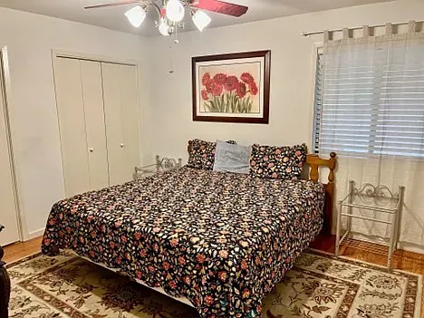 Bedroom with bed, floral bedspread, artwork, window, and closet doors.