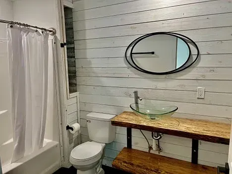A bathroom with a toilet , sink , shower and mirror.
