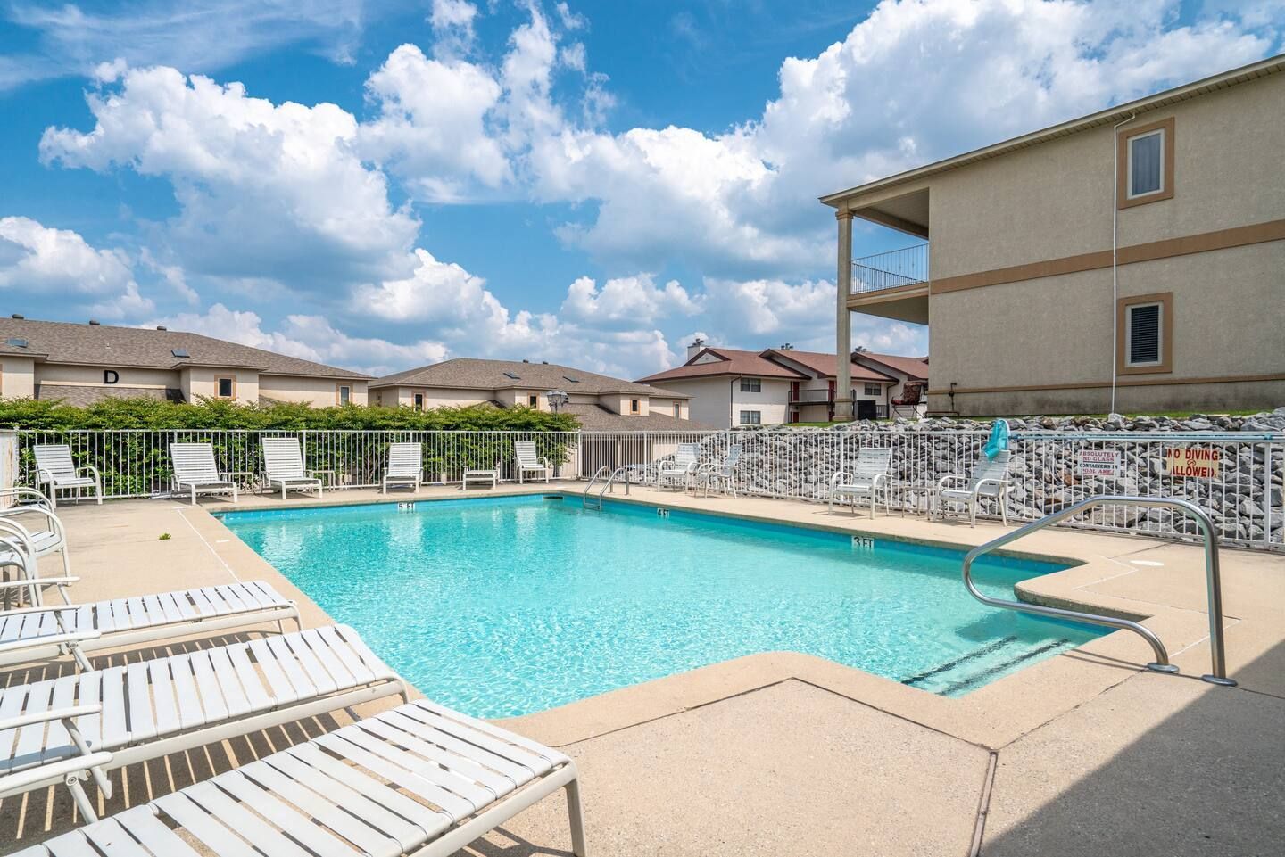 A large swimming pool surrounded by chairs and a building