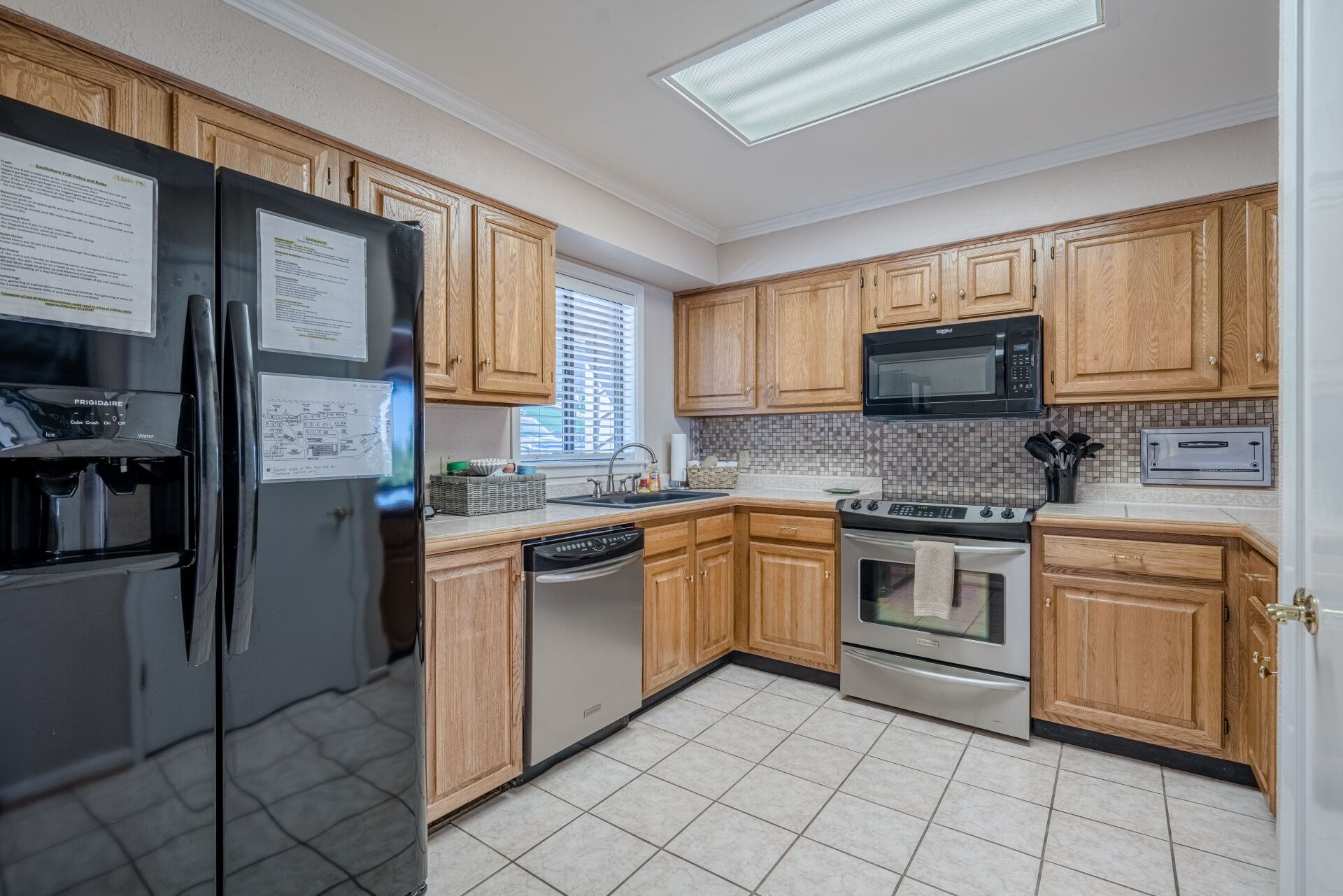 A kitchen with wooden cabinets , stainless steel appliances and a black refrigerator.
