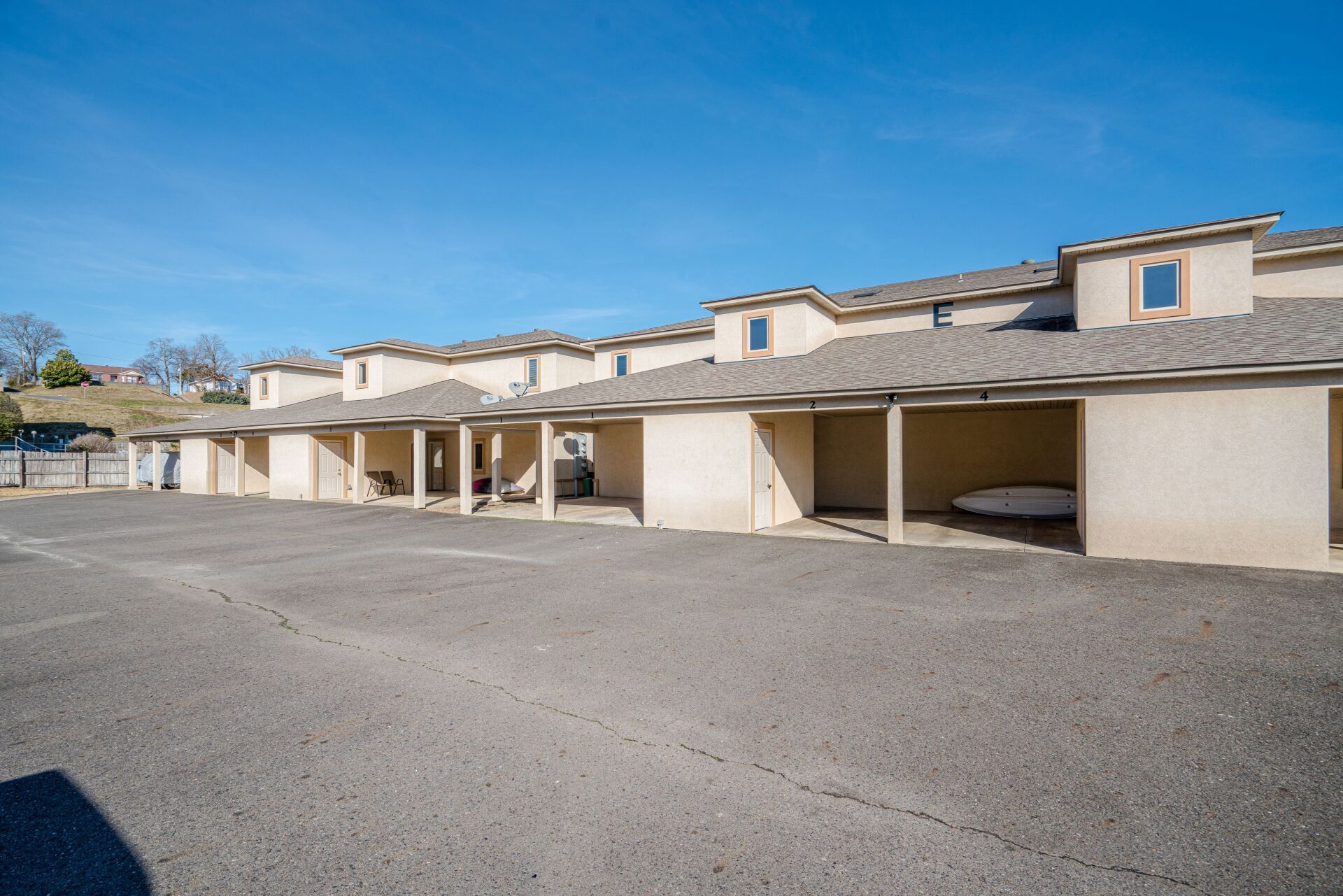 A row of motel buildings with a parking lot in front of them.