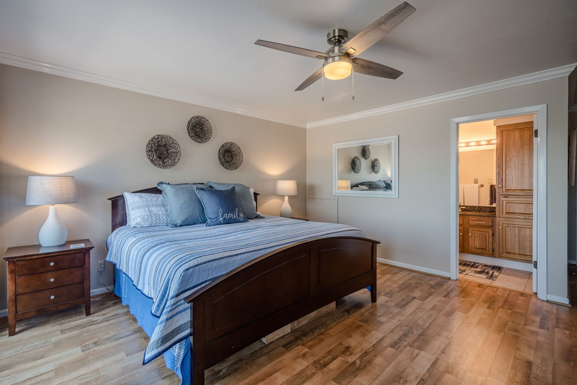A bedroom with a bed , nightstands , lamps and a ceiling fan.