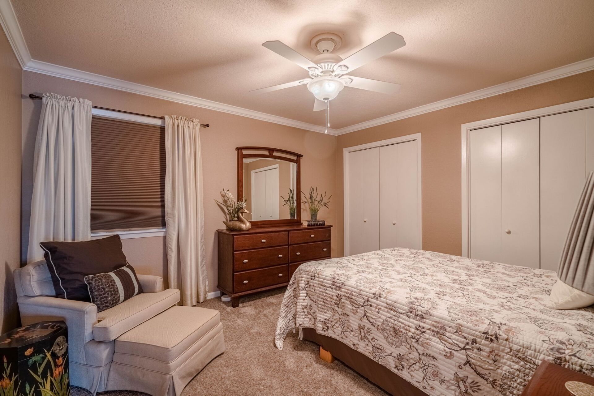 A bedroom with a bed , dresser , mirror and ceiling fan.