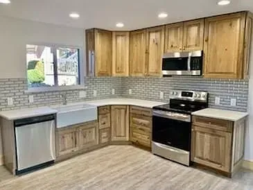 A kitchen with wooden cabinets , stainless steel appliances , a sink , and a window.