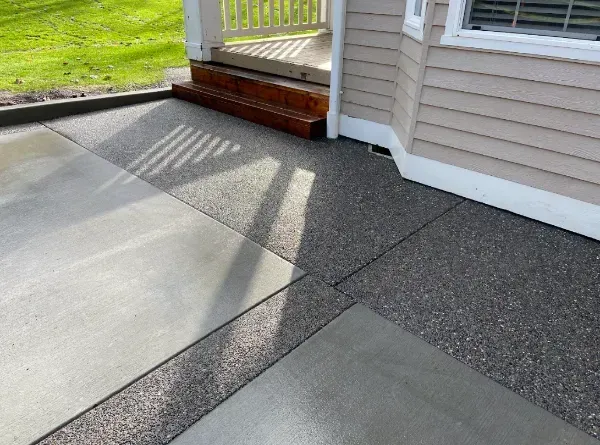 A concrete porch with a red door in front of a house.