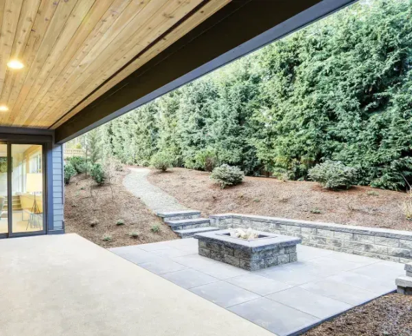 A patio with a fire pit and trees in the background