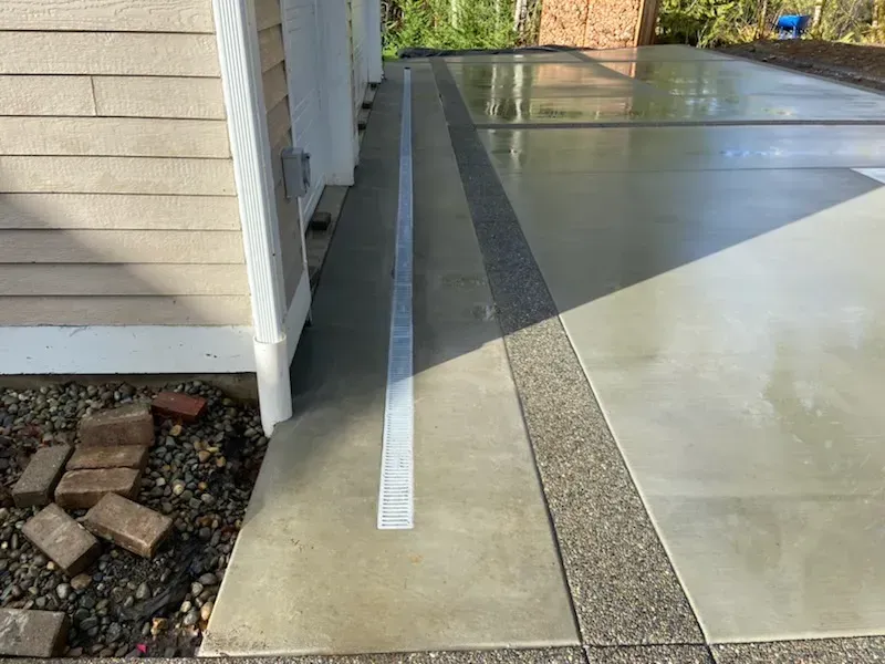 A concrete driveway with a white line on it next to a house.