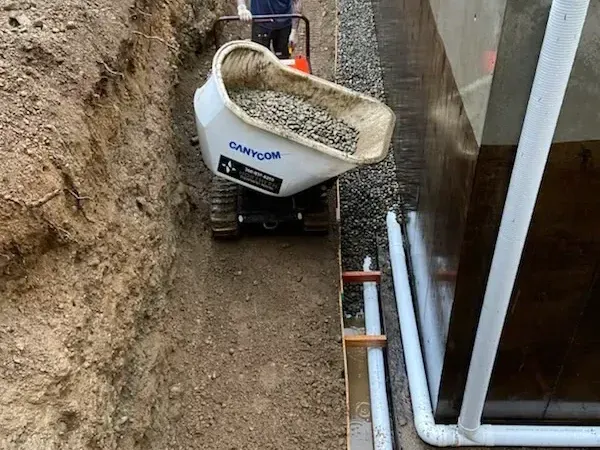 A person is loading dirt into a dump truck.