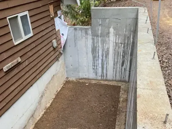 A concrete wall with a hole in it next to a house.