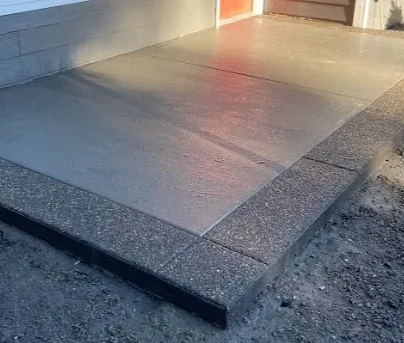 A concrete walkway is being built next to a garage door.