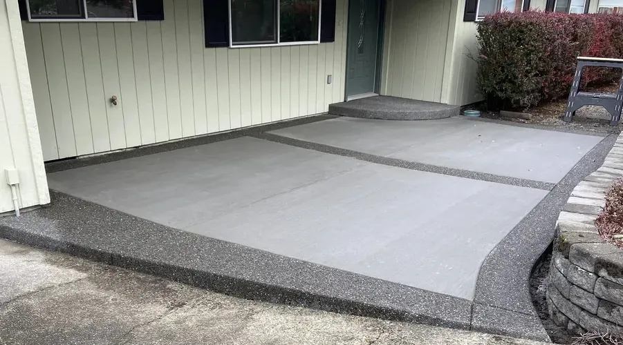 A concrete porch with a red door in front of a house.