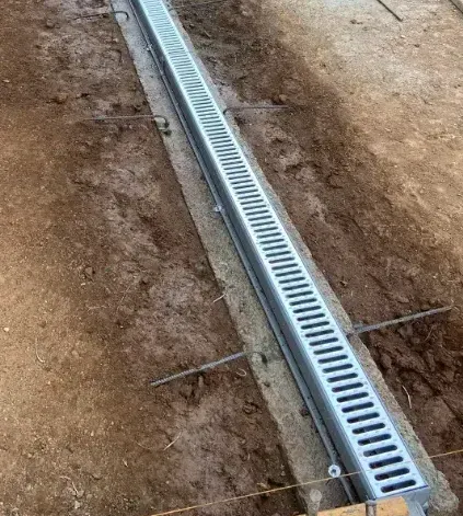 A metal drain is being installed in the dirt.