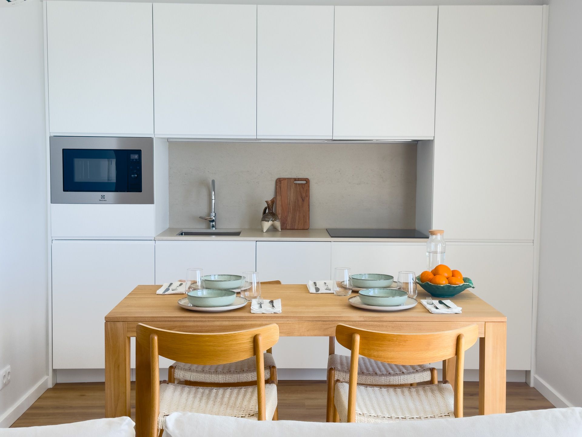 Uma cozinha com mesa, cadeiras e micro-ondas
