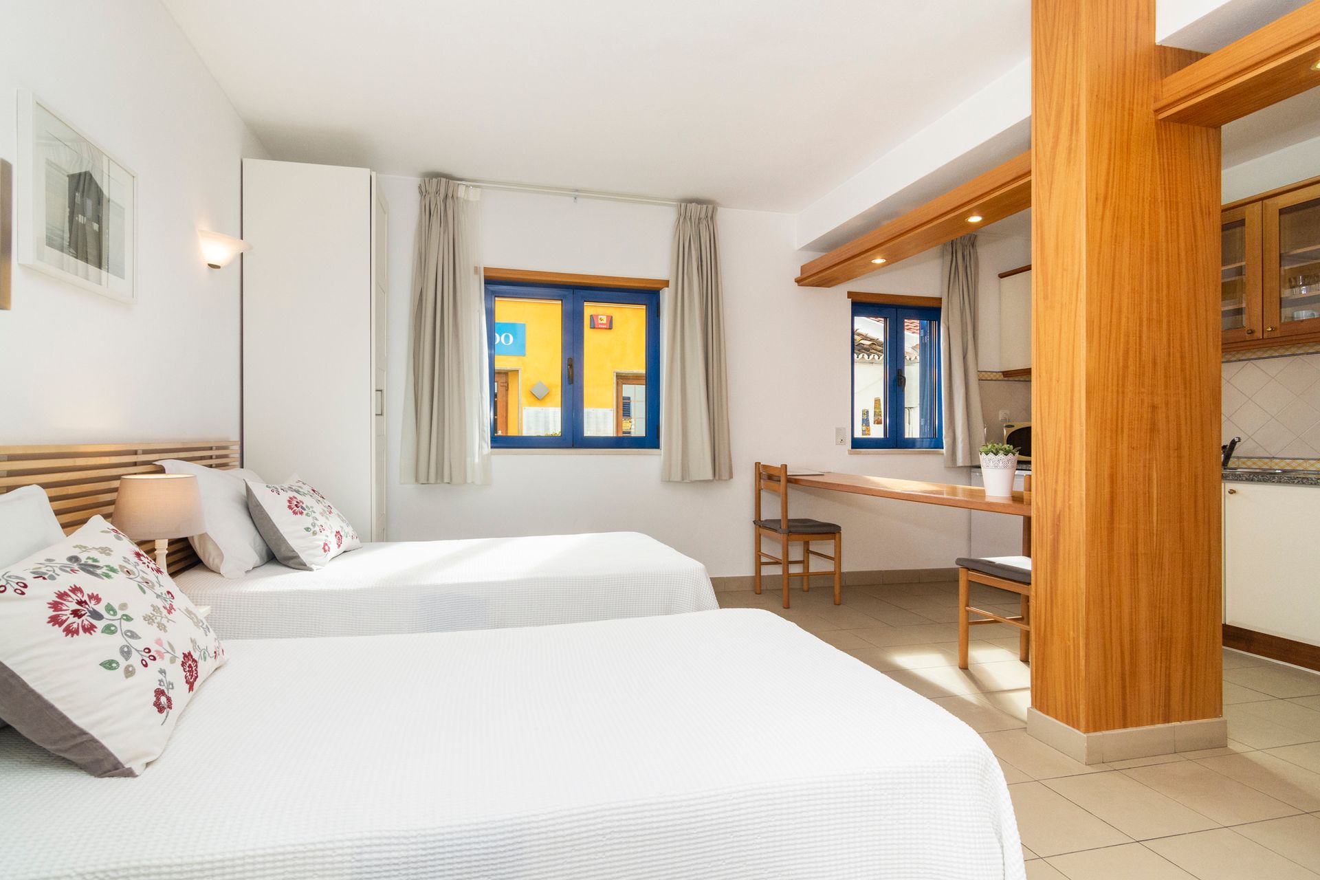 Um quarto de hotel com duas camas, uma escrivaninha e uma varanda.