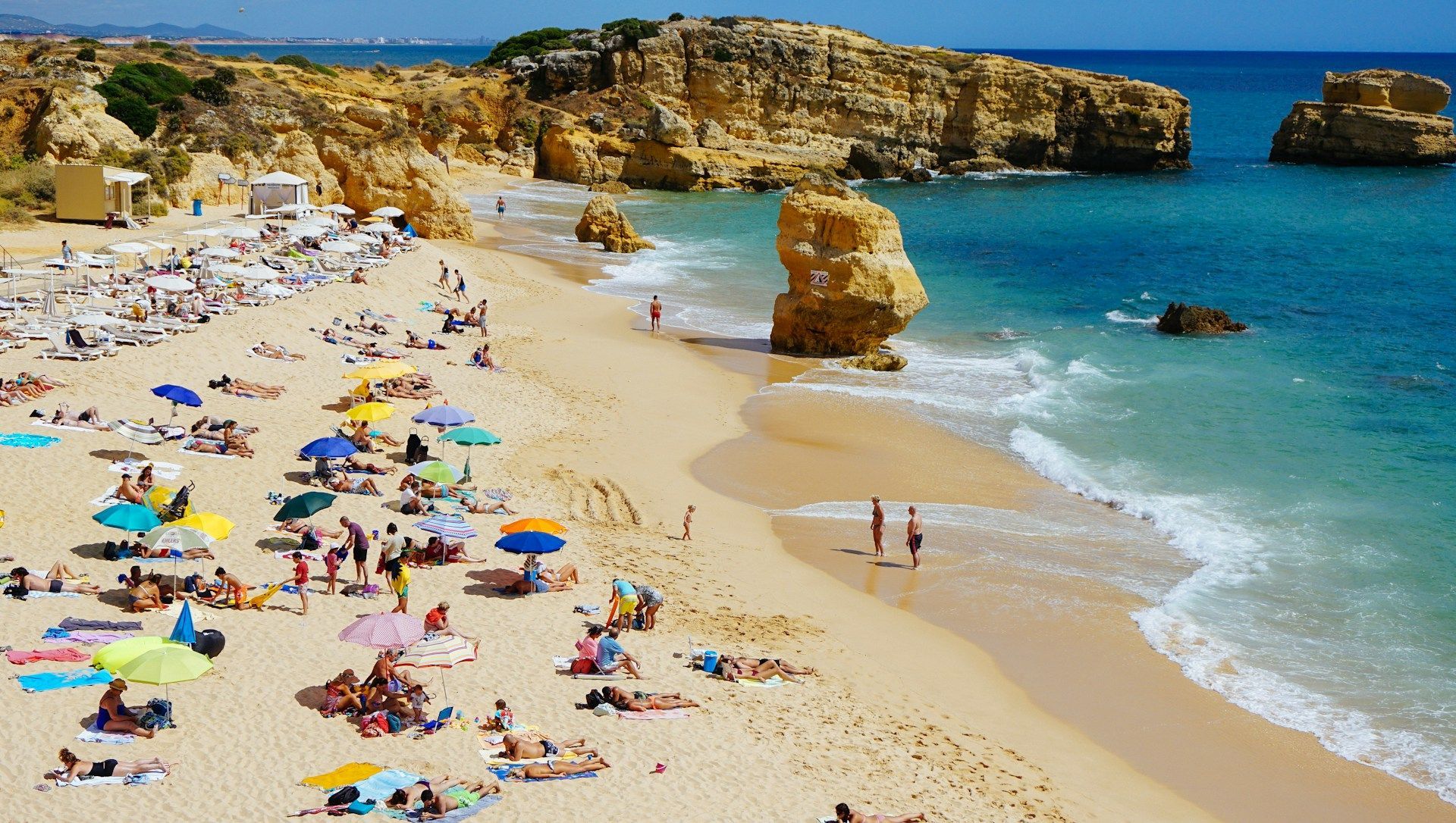 Uma praia cheia de pessoas e guarda-sóis em um dia ensolarado
