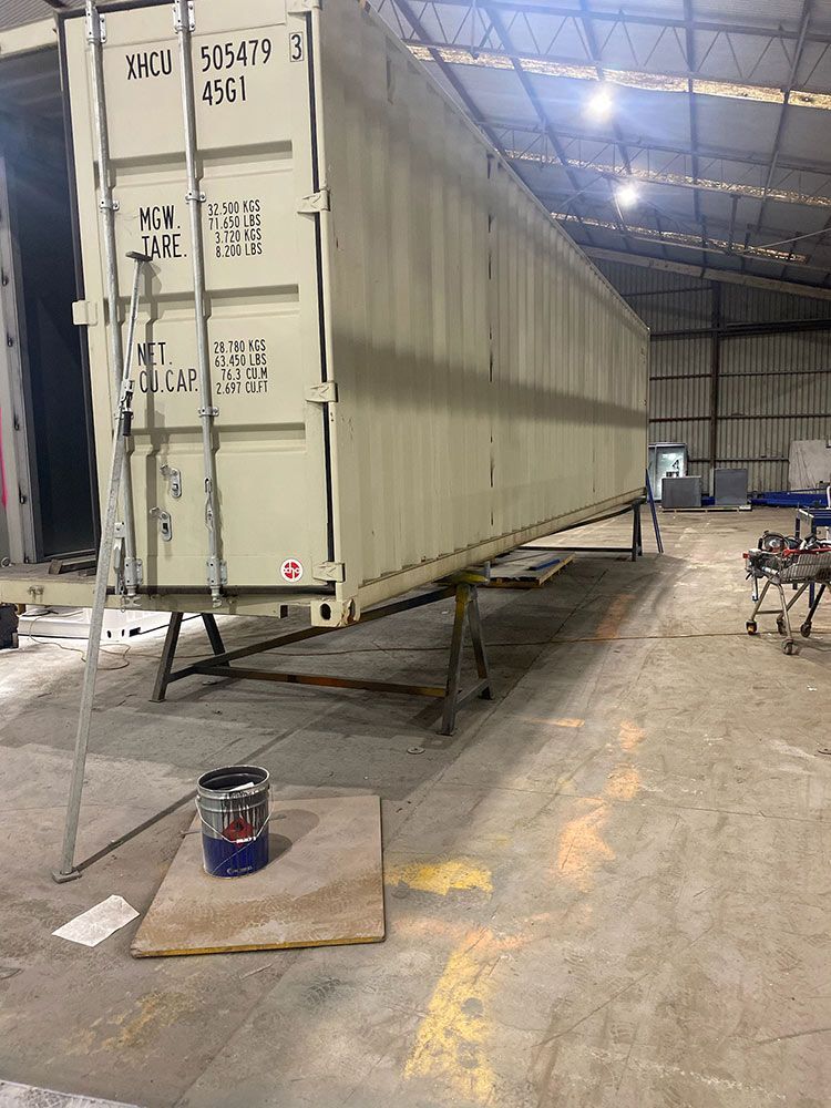 A Large Shipping Container Is Sitting In A Warehouse — Oz Shipping Containers in Teralba, NSW