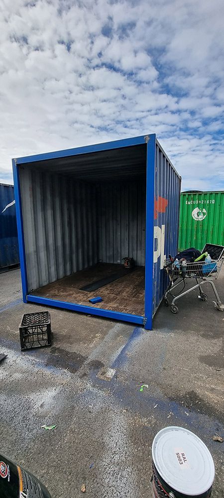 A Blue Shipping Container Is Sitting On The Ground In A Parking Lot — Oz Shipping Containers in Coffs Harbour, NSW