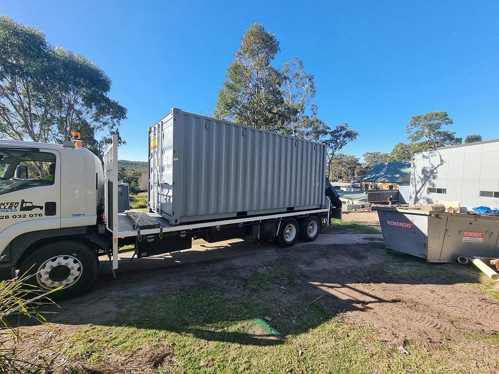 A Truck Is Carrying A Shipping Container On The Back Of It — Oz Shipping Containers in Teralba, NSW