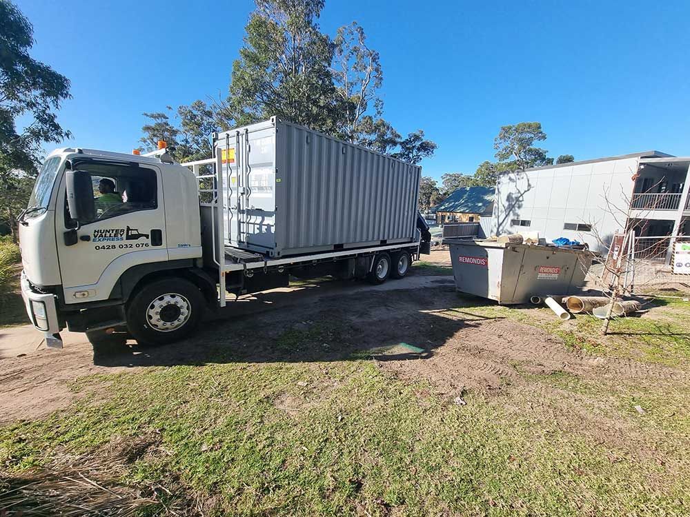 A Truck With a Container on the Back is Parked in a Grassy Field — Oz Shipping Containers in Teralba, NSW