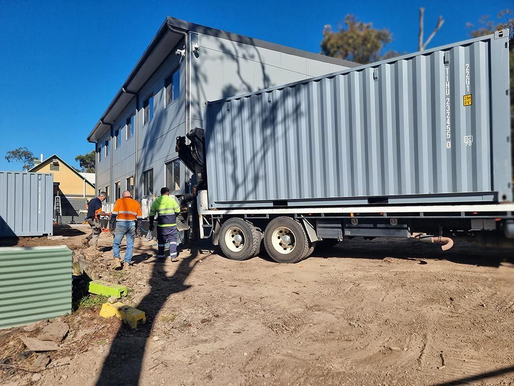 A Large Shipping Container Is Being Loaded Onto A Truck — Oz Shipping Containers in Teralba, NSW