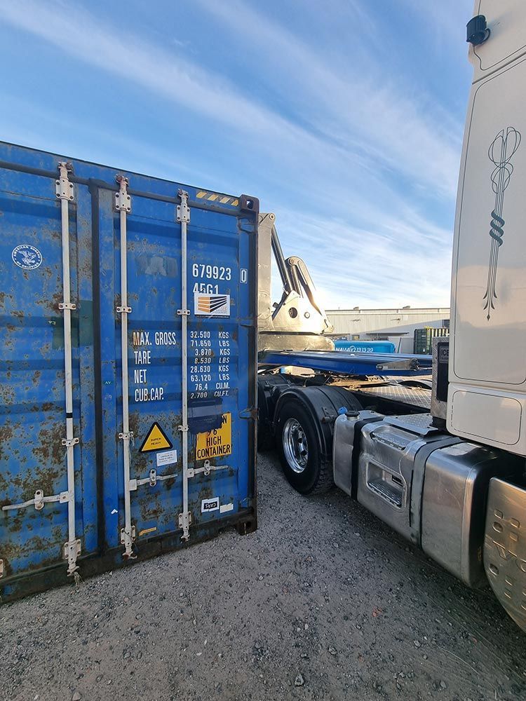 A Blue Shipping Container Is Parked Next To A White Semi Truck — Oz Shipping Containers in Teralba, NSW