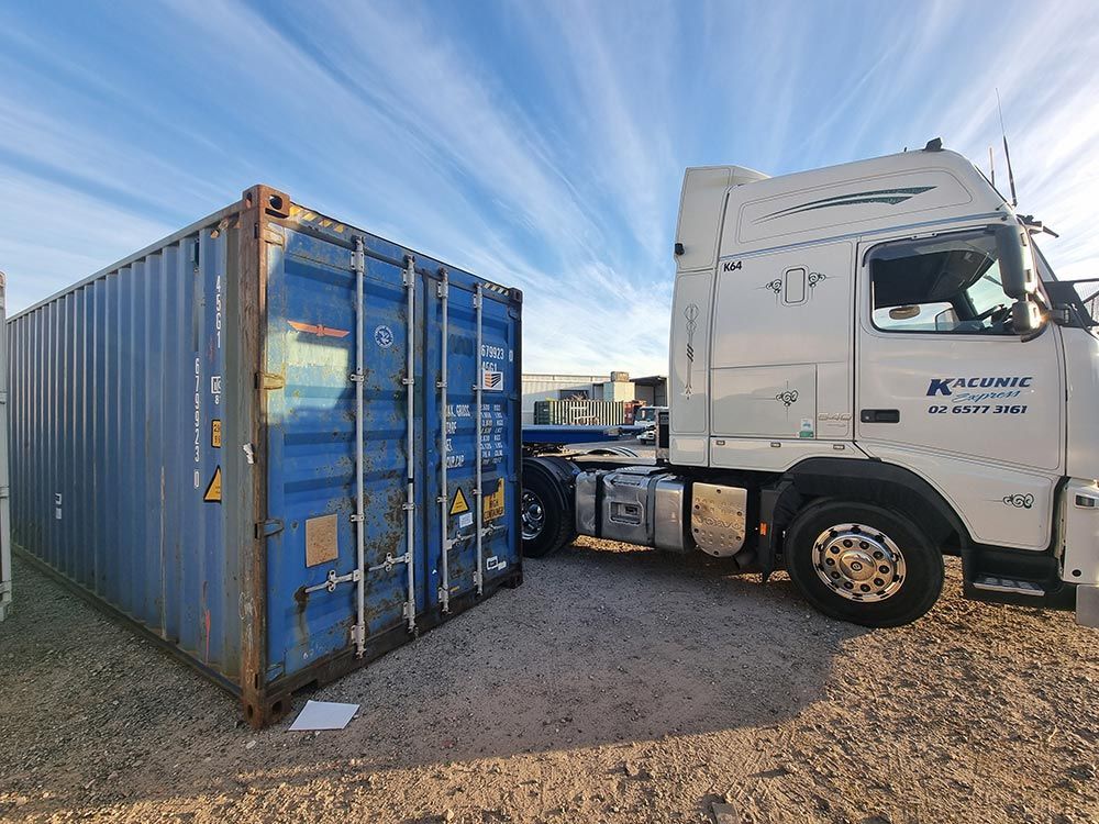 A Semi Truck Is Parked Next To A Blue Shipping Container — Oz Shipping Containers in Teralba, NSW
