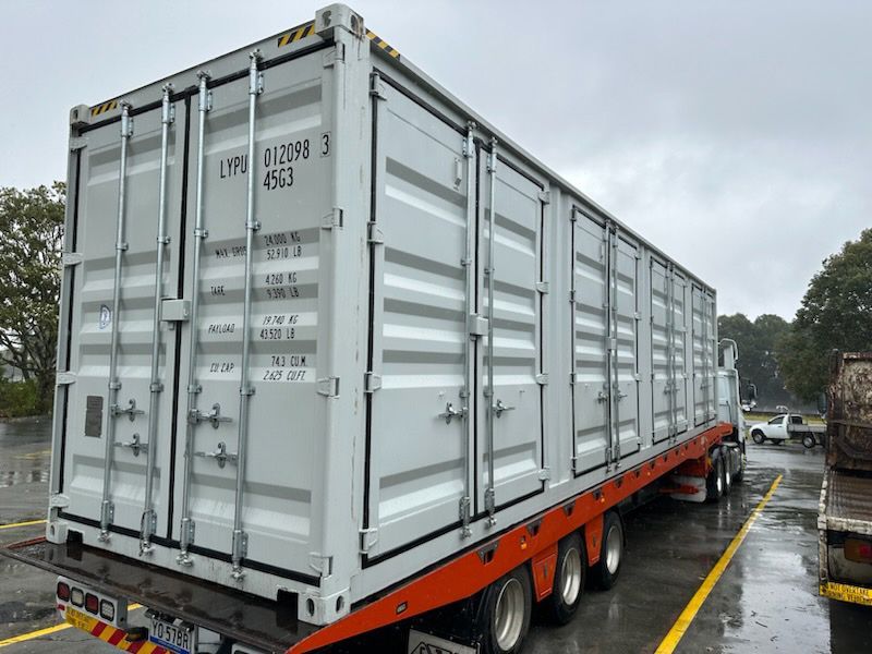 A Large Shipping Container Is On A Trailer In A Parking Lot — Oz Shipping Containers in Teralba, NSW