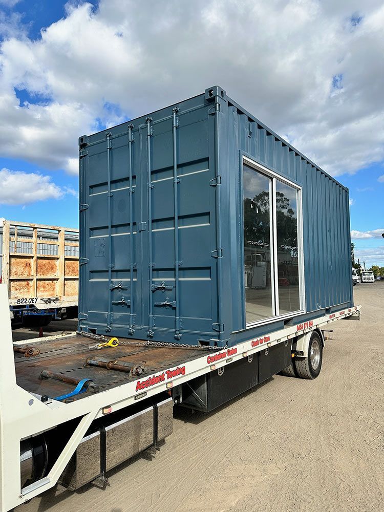 A Blue Shipping Container Is Sitting On Top Of A Tow Truck — Oz Shipping Containers in Teralba, NSW