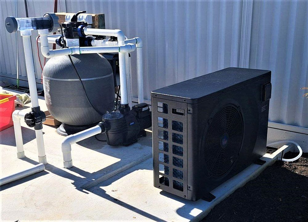 A Swimming Pool Heater is Sitting Next to a Sand Filter — Taree Pool Supplies in Taree, NSW