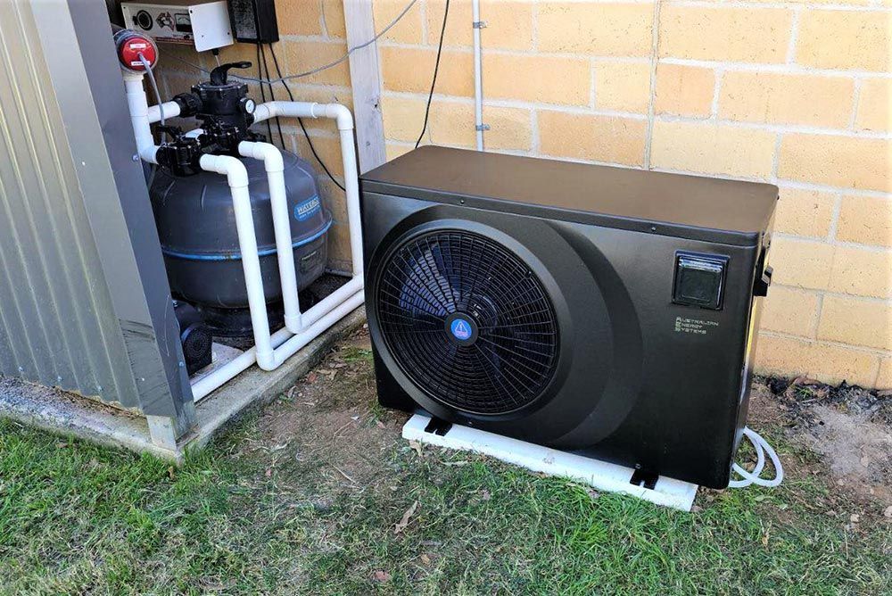 A Swimming Pool Heater is Sitting Next to a Brick Wall — Taree Pool Supplies in Forster, NSW