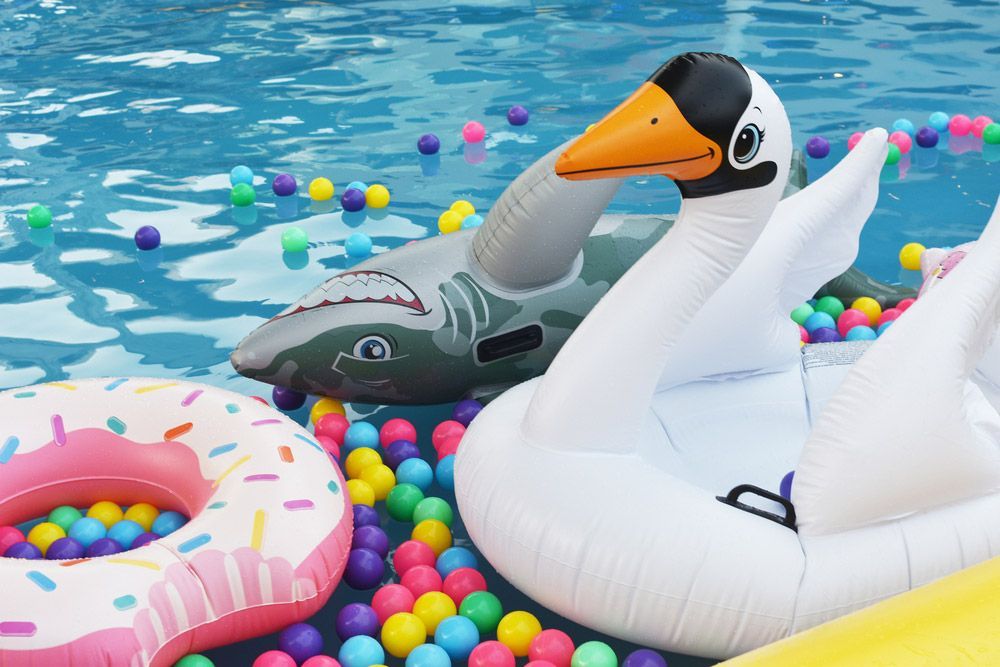 A Swan Float is Floating in a Pool Surrounded by Colourful Balls — Taree Pool Supplies in Taree, NSW