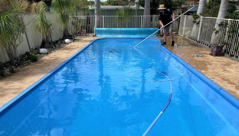 A man maintaining and cleaning a pool with a broom and filter system in Taree