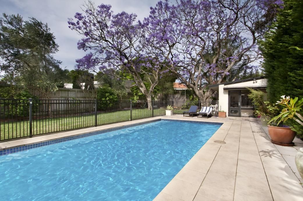 A Large Swimming Pool With Purple Flowers in the Background — Taree Pool Supplies in Taree, NSW