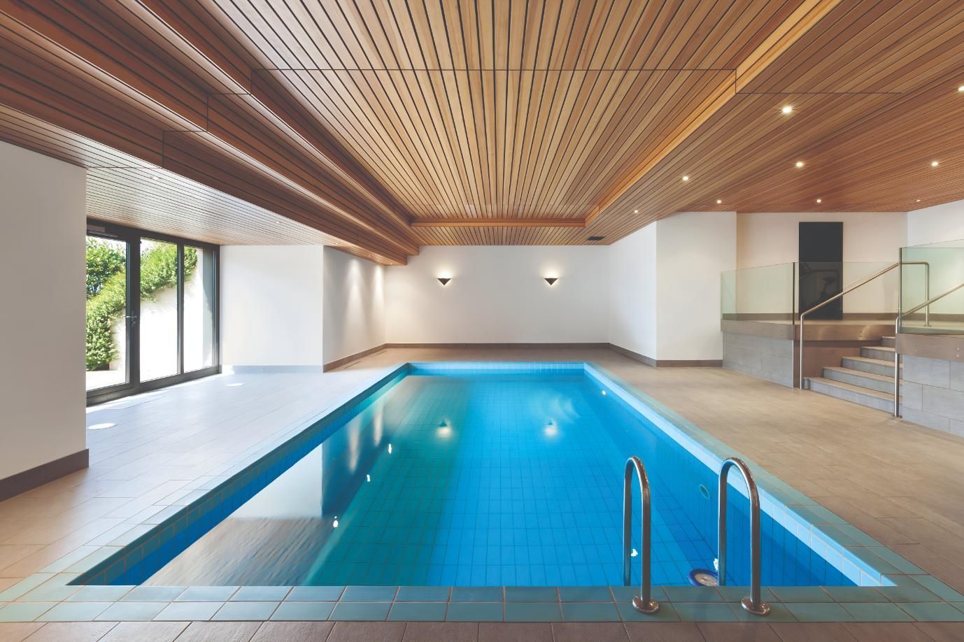 An Indoor Swimming Pool With a Wooden Ceiling and Stairs — Taree Pool Supplies in Forster, NSW