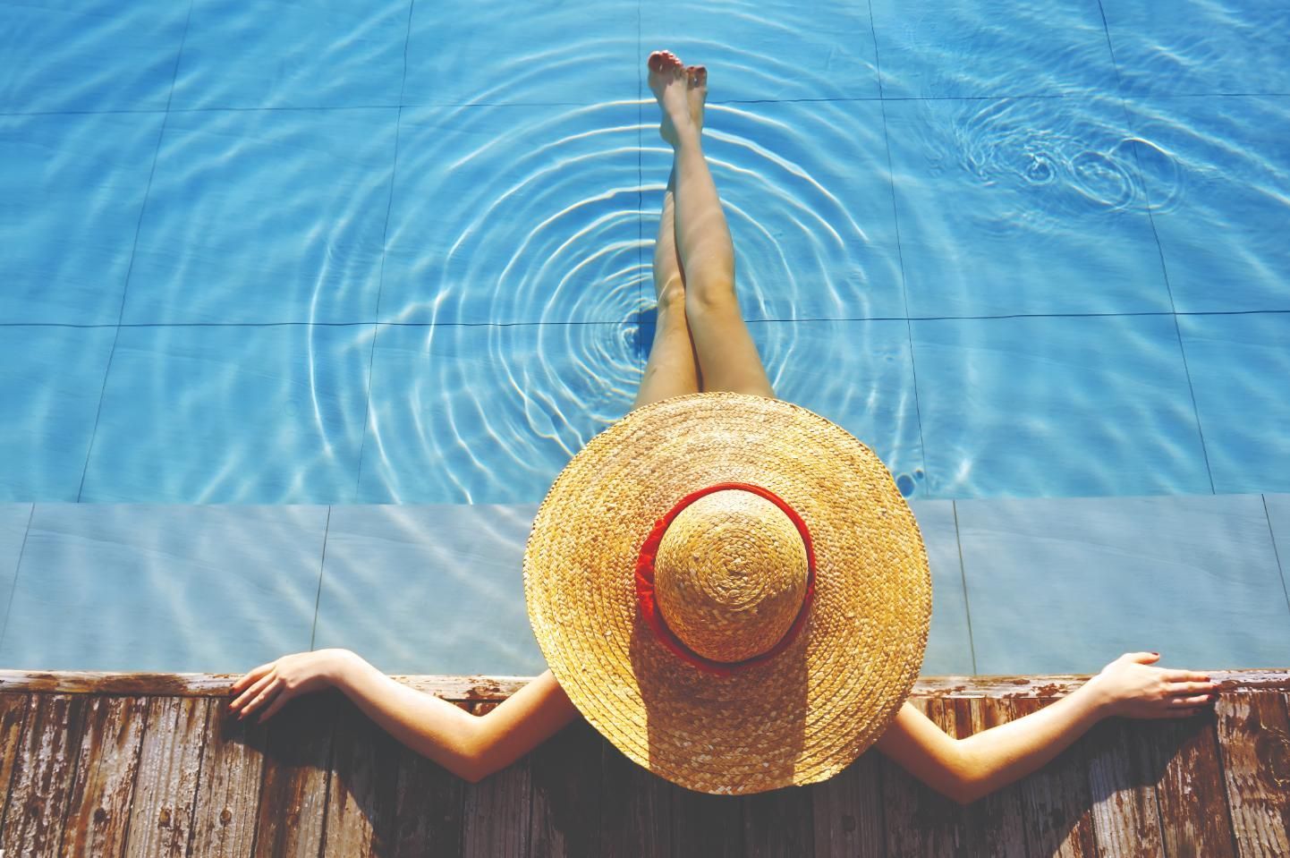 A Woman in a Straw Hat is Laying on the Edge of a Swimming Pool — Taree Pool Supplies in Forster, NSW