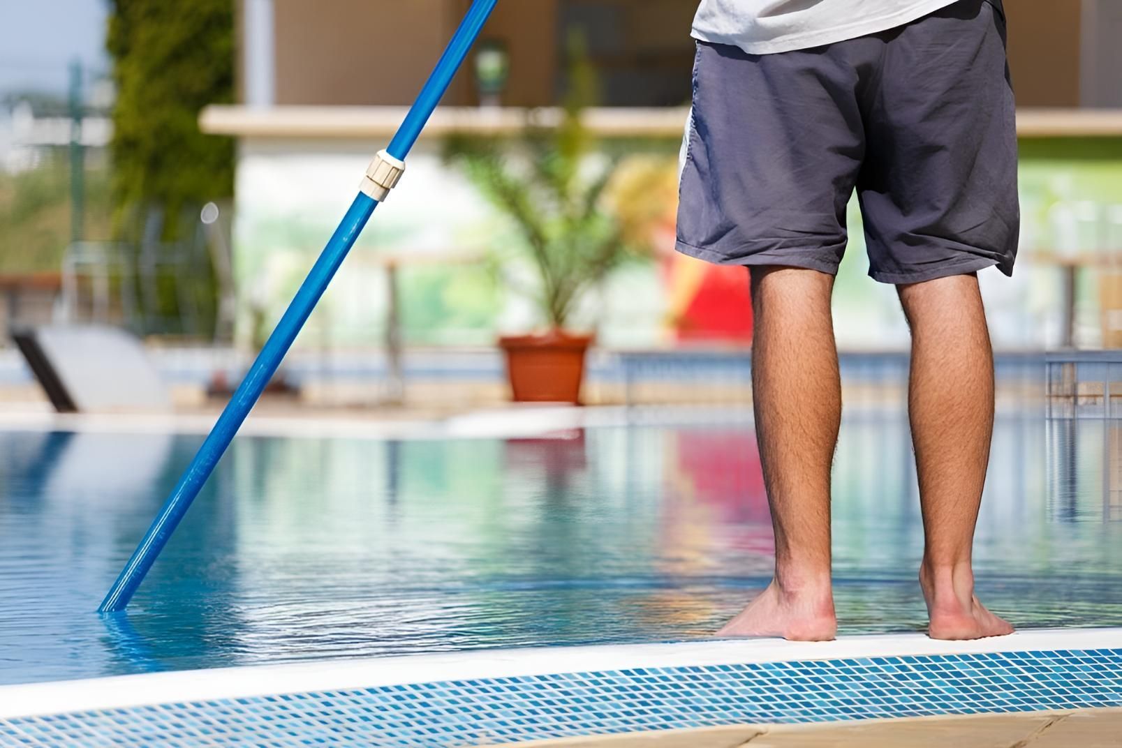 A man standing on the edge of a pool, maintaining the pool with supplies from a Forster Pool shop.