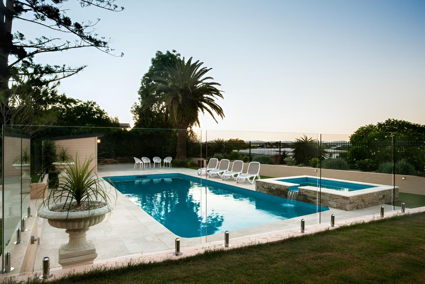 A Large Swimming Pool With a Glass Fence Around It — Taree Pool Supplies in Hallidays Point, NSW