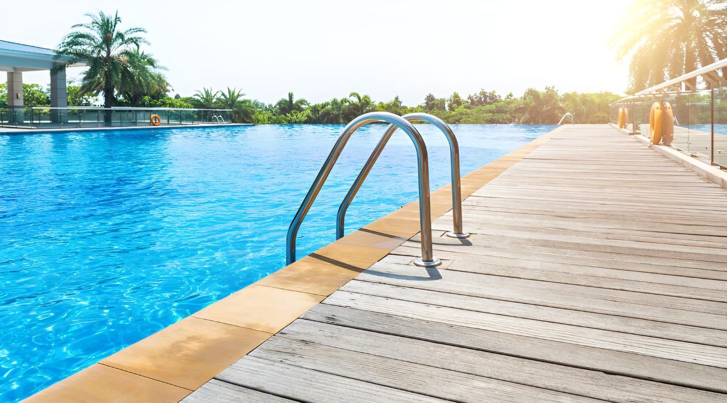 A Swimming Pool With a Wooden Deck and Stairs Leading to It — Taree Pool Supplies in Taree, NSW