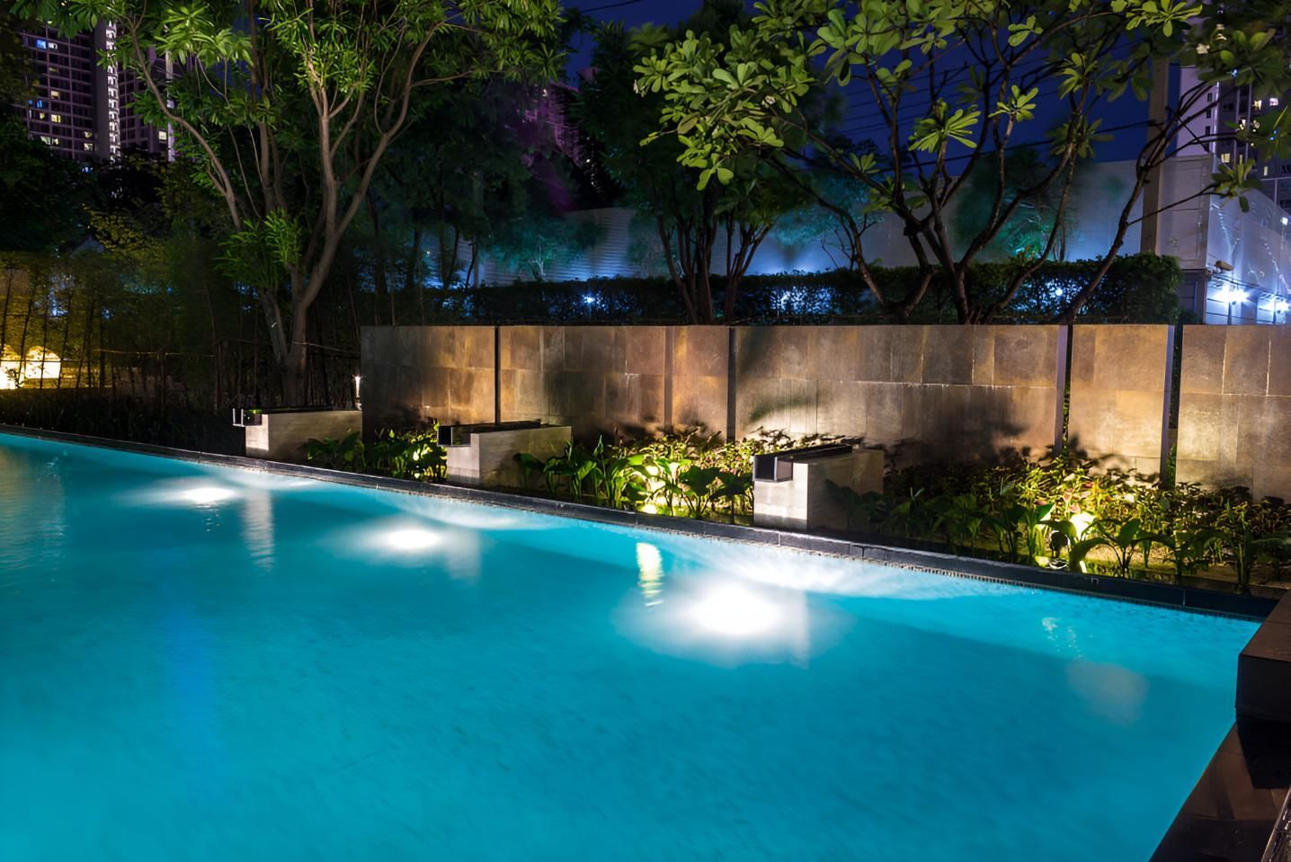 A Large Swimming Pool is Lit Up at Night — Taree Pool Supplies in Forster, NSW