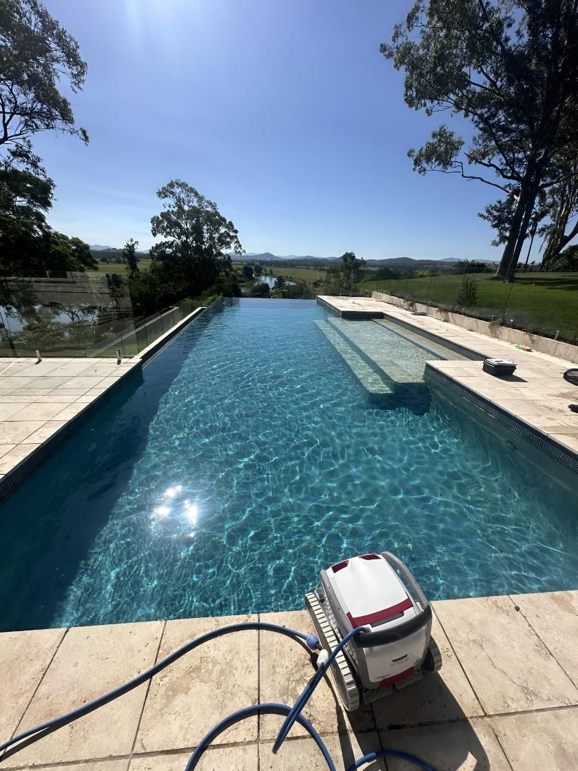 A Robotic Pool Cleaner is Sitting Next to a Large Swimming Pool — Taree Pool Supplies in Forster, NSW