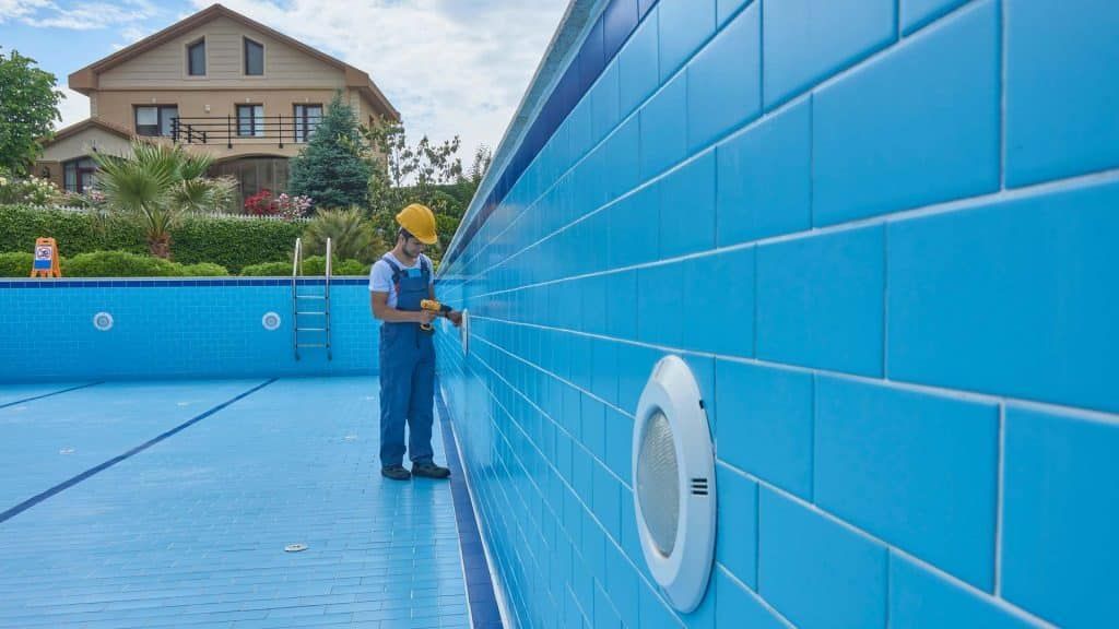 A Man is Working on the Side of a Swimming Pool — Taree Pool Supplies in Old Bar, NSW